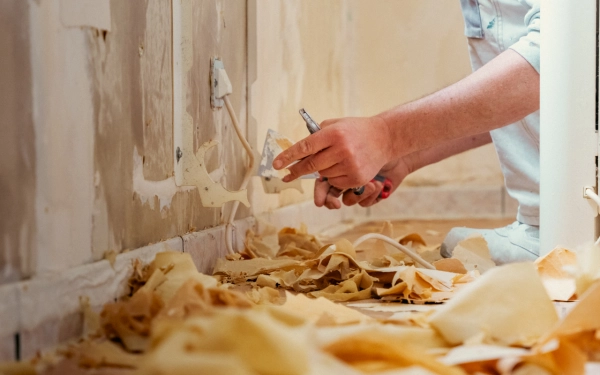 Artisan en train de décoller du papier peint dans une maison à Épron, lors d’un chantier de rénovation complète Analytics TRAVAUX.