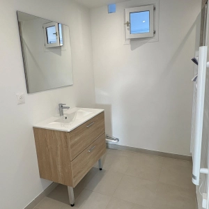 Salle de bain rénovée, meuble vasque en bois, carrelage clair, sèche-serviette, fenêtre en verre dépoli