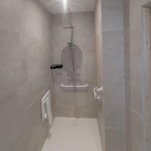 Douche avec receveur encastré, barres de maintien, siège repliable et robinetterie adaptée