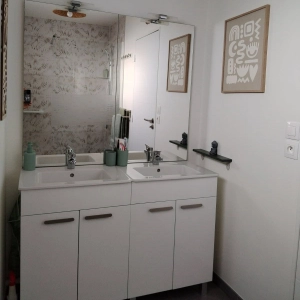 Rénovation de salle de bain dans le Calvados, design minimaliste, vue sur meuble double vasque avec miroir éclairé.