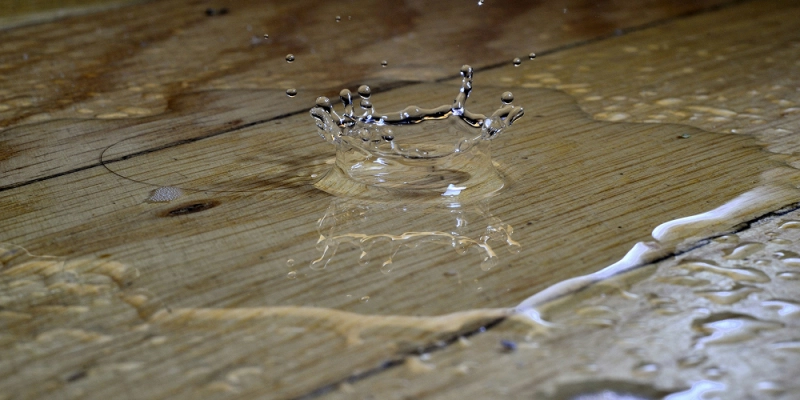 Goutte d'eau s'écrasant sur un sol en bois, représentant une urgence fuite d'eau en plomberie