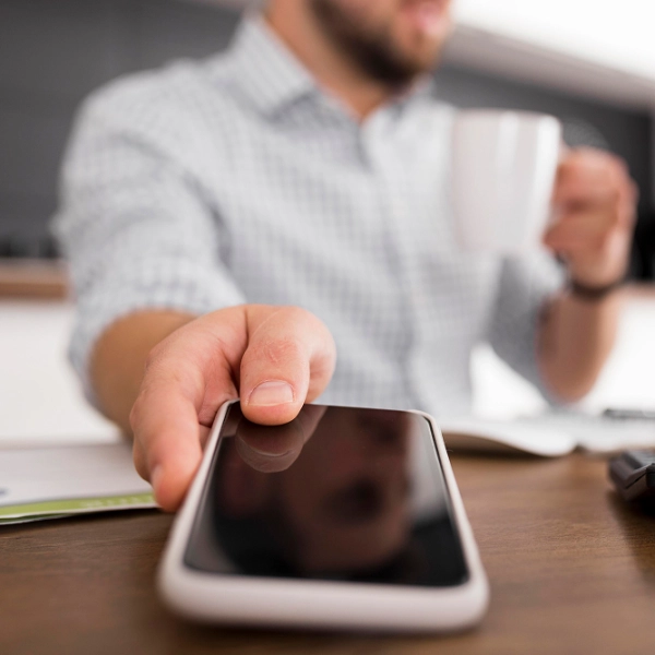Homme tenant un smartphone au bureau, prêt à appeler notre service de dépannage d'urgence