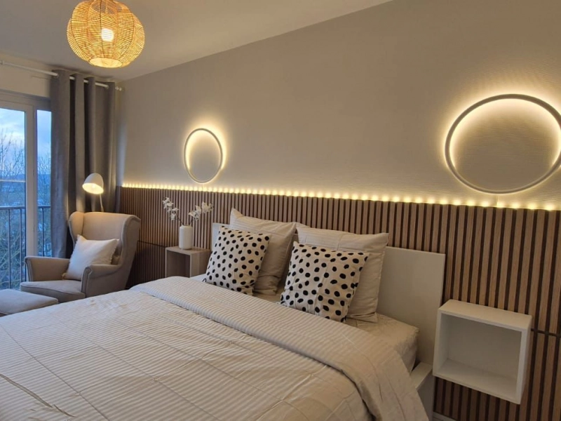Chambre rénovée par Analytics TRAVAUX, tons beiges et lumières murale