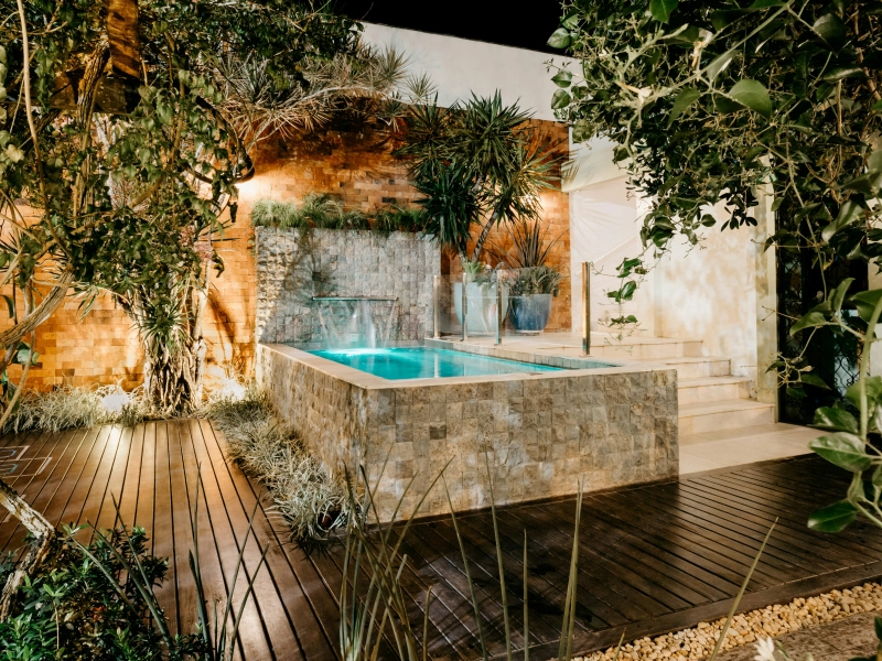 Piscine et jets d'eau de nuit avec éclairage et terrasse tout autour